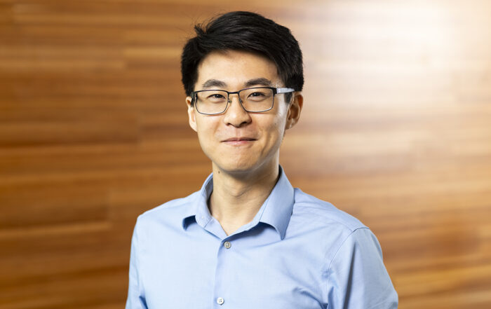 Professor Jerry Li stands against a wood paneled background